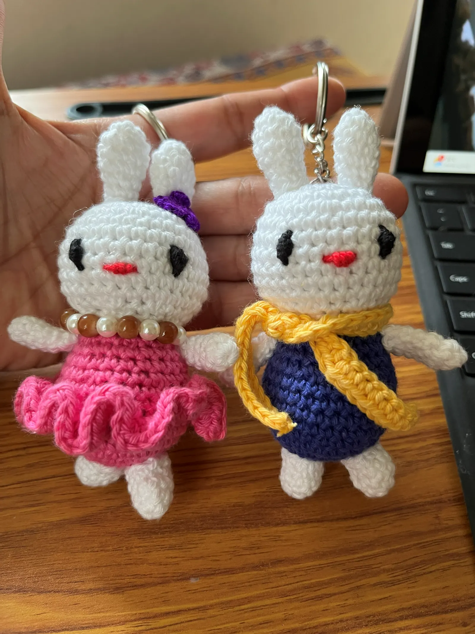 Pair of white bunny crochet keychains in colorful outfits