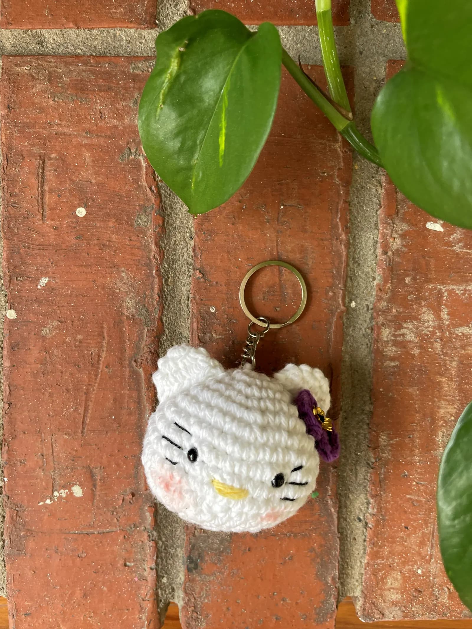 White cat-face crochet keychain with purple bow